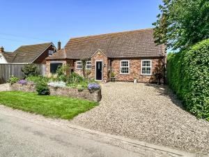 a house with a gravel driveway in front of it at Lilium Cottage in North Somercotes