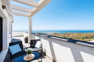 Un balcón con sillas, una mesa y el océano en Nuevo Atico Panoramico - Piscina - 3 habitaciones - Terraza vista Mar, en Rincón de la Victoria