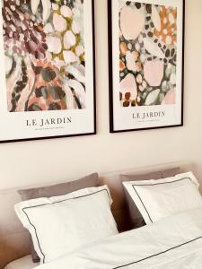 dwa ramowane grafiki nad łóżkiem z dwoma poduszkami w obiekcie Jardin Apartment Ursynów w Warszawie
