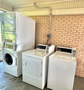 a laundry room with white appliances and a brick wall at Relax Inn Mcgehee in McGehee