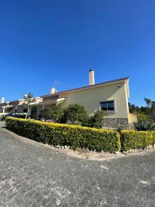 une maison avec une haie devant elle dans l'établissement Paraíso do Quim, à São Martinho do Porto