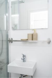 W białej łazience znajduje się umywalka i lustro. w obiekcie Gemütliche 2-Zimmer-Wohnung w mieście Neustadt in Holstein