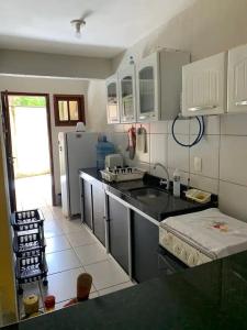 une cuisine avec des placards blancs et un comptoir noir dans l'établissement Chalé em Guaramiranga, à Guaramiranga