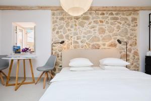 ein Schlafzimmer mit einem weißen Bett und einer Steinwand in der Unterkunft Stone Elegance in Dubrovnik