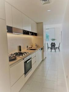 una cucina con armadi bianchi, tavolo e sedie di Nissaki@Terrigal - Luxury Studio Apartment a Terrigal