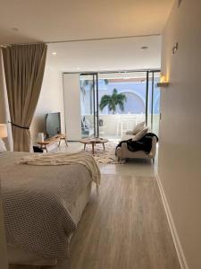 a bedroom with a bed and a chair and a balcony at Nissaki@Terrigal - Luxury Studio Apartment in Terrigal