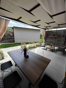 un patio con una mesa de madera, sillas y una pantalla en •Naiades Villas•Meliti•, en Ladharió
