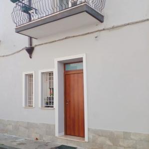 モンドラゴーネにあるCasa Margherita piano primoの木製のドアとバルコニーが備わる白い家