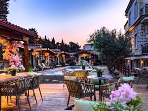 eine Terrasse mit Tischen und Stühlen neben einem Pool in der Unterkunft Etiz Hotels Alaçatı in Cesme