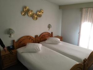 two twin beds in a bedroom with a heart sign on the wall at Hôtel de la Plage à Gland in Gland