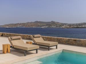 dwa leżaki i basen przy wodzie w obiekcie Star villa by Bestofmikonos w mieście Mykonos