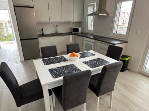 a kitchen with a white table with chairs and an orange on it at Beachouse Villa Tatijana in Rogoznica