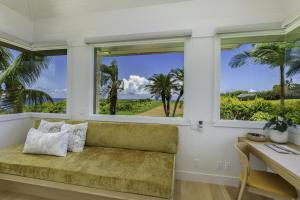 Habitación con sofá, escritorio y ventanas. en Hale Lani home, en Kilauea