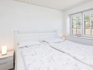 a white bedroom with a bed and a window at Apartment Hanstholm in Hanstholm