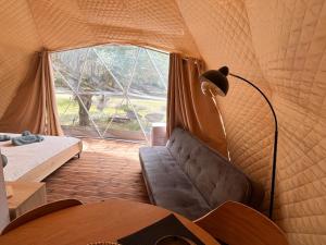 a room with a couch in a tent with a window at Manna Gea Glamping Domes in Vonitsa