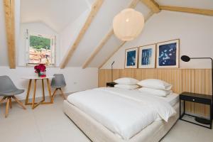um quarto com uma cama branca, uma mesa e cadeiras em Stone Elegance em Dubrovnik