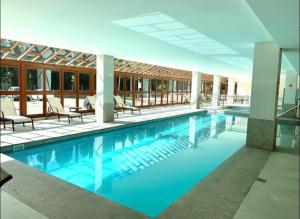 a large swimming pool with blue water in a building at Vista da Pedra Flat em Pedra Azul in Pedra Azul