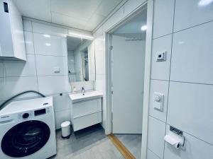 bagno bianco con lavatrice e lavandino di Lofoten Studio Penthouse a Svolvær