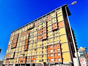Sweety Bela Vista Apartment في لشبونة: مبنى طويل مع نوافذ صفراء وبرتقالية