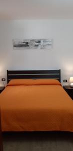 Una cama con colcha naranja encima. en Appartamenti Stella, en Alcamo