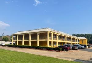 um grande edifício amarelo com carros estacionados num parque de estacionamento em Majestic Inn em Longview