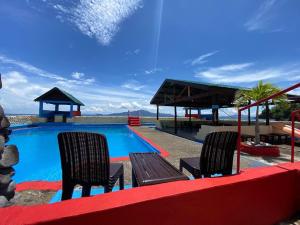 a swimming pool with two chairs and a table at Napo Beach Resort in Maripipi
