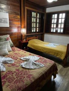 a bedroom with two beds with towels on the bed at Chalé Castelo Interlagos in Santo Amaro