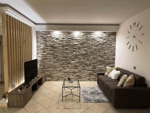 a living room with a couch and a brick wall at Kiro Apartment Experience Pompei in Angri
