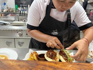 a woman in a kitchen preparing a sandwich and fries at Nalini Resort in Amed