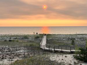 a boardwalk leading to the beach at sunset at Stunning Modern Beach House with Swimming Pool and Spectacular Sunsets in Tiny