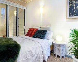 ein Schlafzimmer mit einem weißen Bett mit Kissen darauf in der Unterkunft Cosy Cottage 2 Bedroom Great Location Close to Transport in Sydney