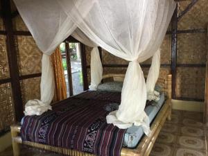 a bedroom with a canopy bed with curtains at Sunset Cottages in Hitokalak