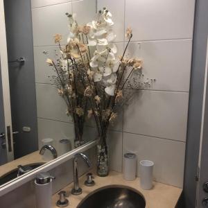 La salle de bains est pourvue d'un lavabo et d'un vase avec des fleurs. dans l'établissement Las Naciones 1710, à Buenos Aires