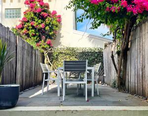 a table and chairs on a patio with pink flowers at Cosy Cottage 2 Bedroom Great Location Close to Transport in Sydney