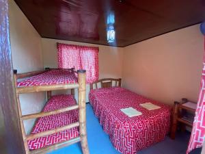 two bunk beds in a room with red sheets at Napo Beach Resort in Maripipi