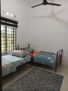 a bedroom with two beds and a ceiling fan at Homestay Lembah Tambunan in Kampong Nail