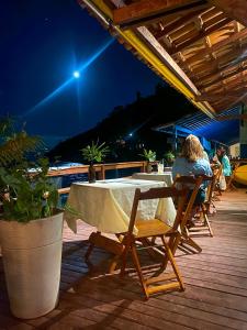 Pousada e Mergulho Dolce Vita في Praia Vermelha: امرأة تجلس على طاولة في الليل