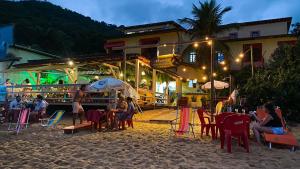 Pousada e Mergulho Dolce Vita في Praia Vermelha: مجموعة من الناس يجلسون على الطاولات على الشاطئ