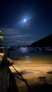 une pleine lune sur une masse d'eau la nuit dans l'établissement Pousada e Mergulho Dolce Vita, à Praia Vermelha