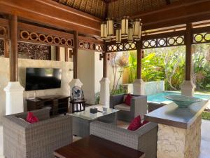 an outdoor living room with a television and a pool at Jimbaran BeachStroll Villa (2BR) in Jimbaran
