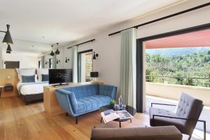- un salon avec un canapé bleu et un lit dans l'établissement Hôtel Sainte Victoire, à Vauvenargues