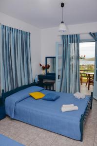 a bedroom with a blue bed with a view of the ocean at Hotel Dina - Ξενοδοχείο Ντινα in Platy