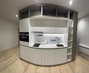 a kitchen with white cabinets and a counter at LHR Apartments in London