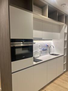 a kitchen with white cabinets and a black microwave at LHR Apartments in London