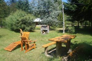 stół piknikowy, 2 krzesła, drewniany stół i ławka w obiekcie Cabañas la osa w mieście El Bolsón