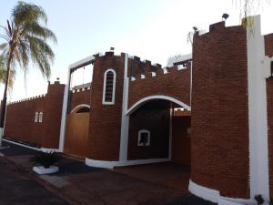 a red brick building with a gate and a palm tree at Medieval Motel e Hospedagem in Ribeirão Preto
