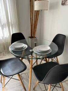 a table with four chairs and a glass table with plates on it at Center Apartment Studio in Buenos Aires