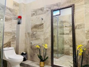 a bathroom with a toilet and a glass shower at Hostal Gautamas Guest rooms, hostal para viajeros,backpackers hostel in Tepoztlán