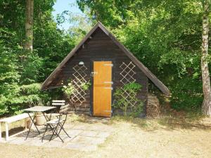 ein kleiner Schuppen mit einer Holztür und einem Tisch in der Unterkunft Holiday home Tisvildeleje XVIII in Tisvildeleje