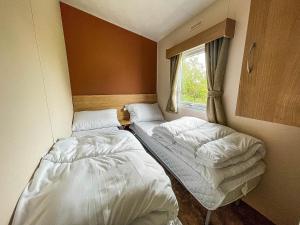 2 camas en una habitación pequeña con ventana en Homely 8 Berth Caravan In Southview Holiday Park, Ref 33048tc en Skegness